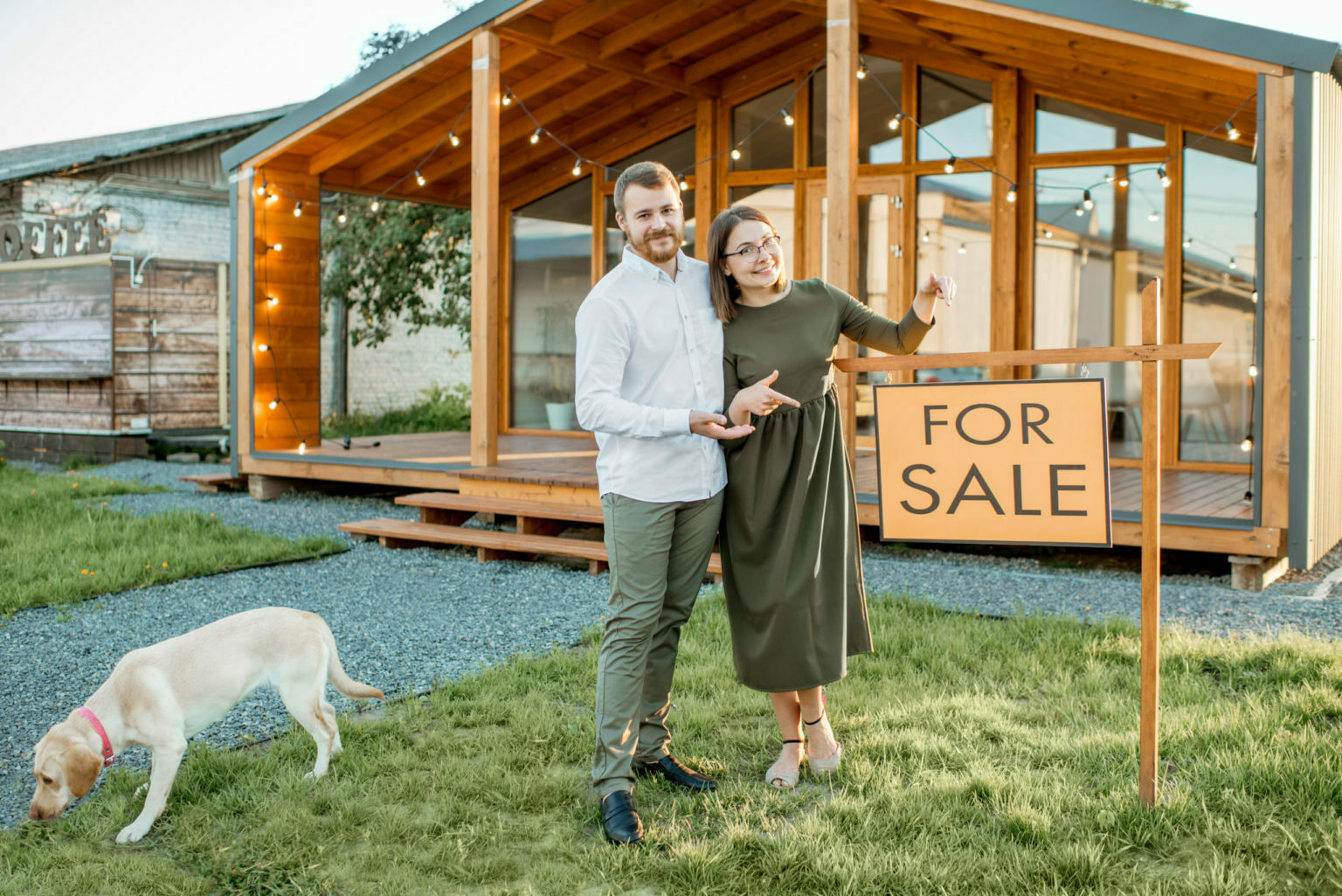 a man and woman posing for a picture with a dog and a sign