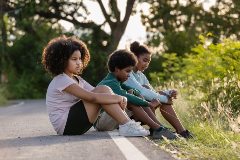 a person and a boy sitting on a curb