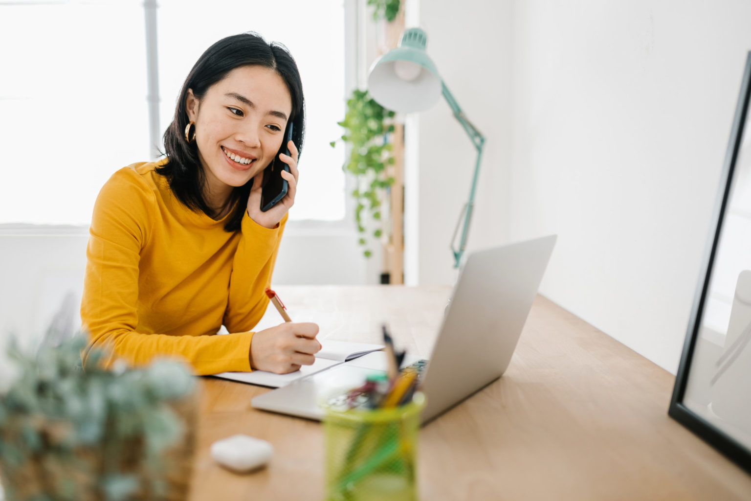 Woman talking on her mobile phone while working with a laptop