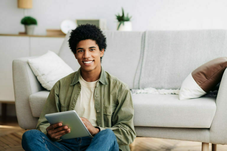 Web based learning. Positive black male student with tablet computer looking at camera and smiling