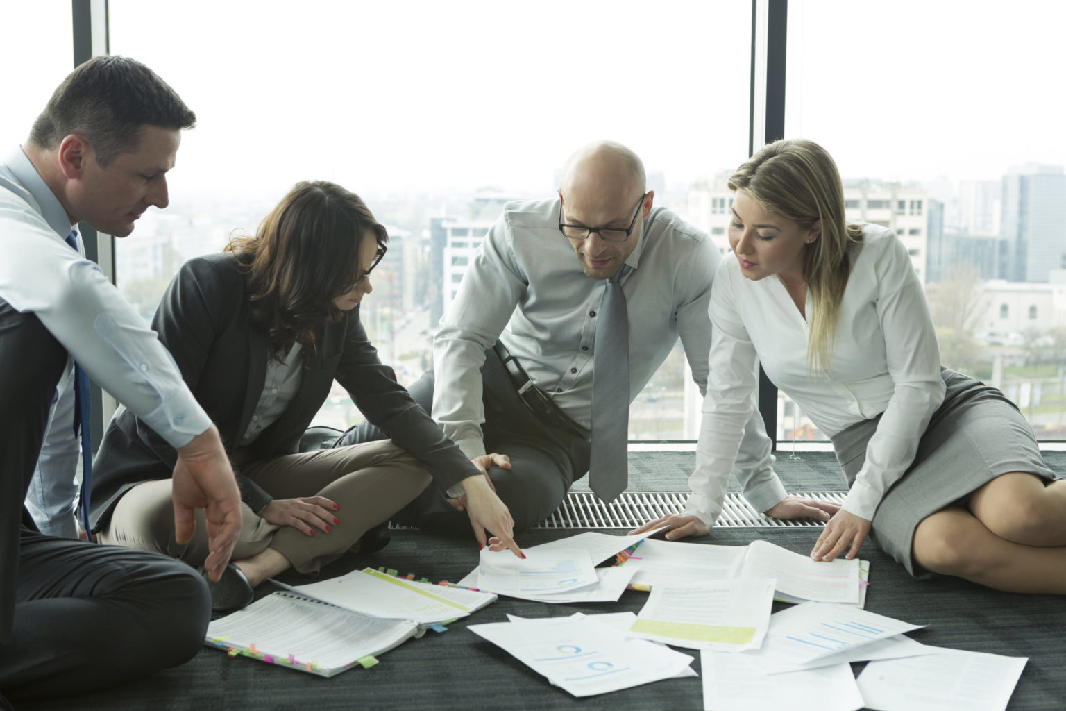 Businesspeople sitting on floor discussing papers