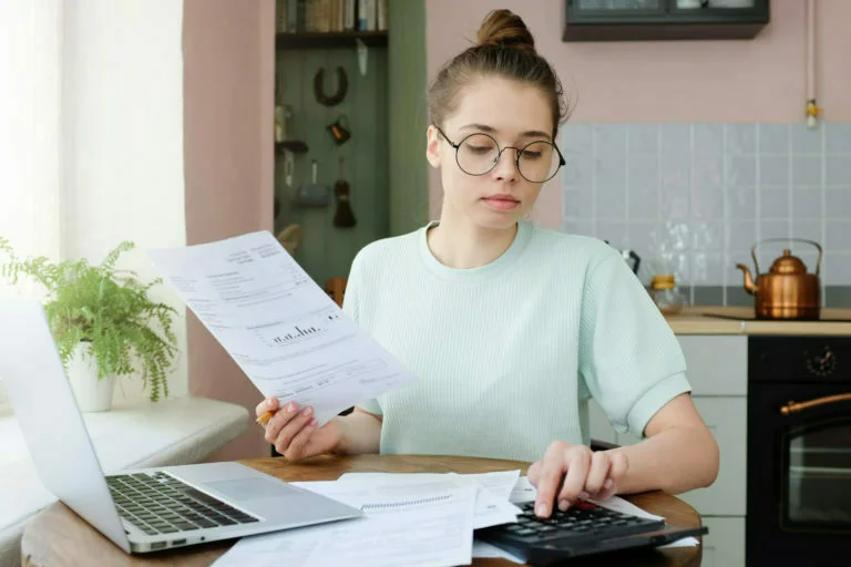 Young beautiful woman budgeting, managing utilities expenses, writing financial plan
